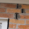A brick wall displaying stair-step cracks and messy tuckpointing on a Green Valley home